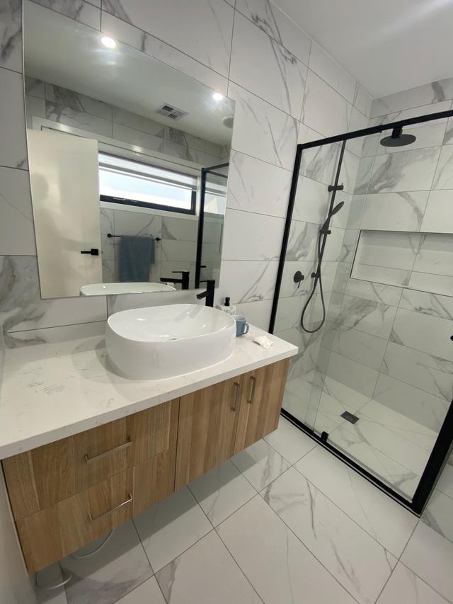 Completed bathroom renovation with a timber vanity, vessel basin and frameless shower screen