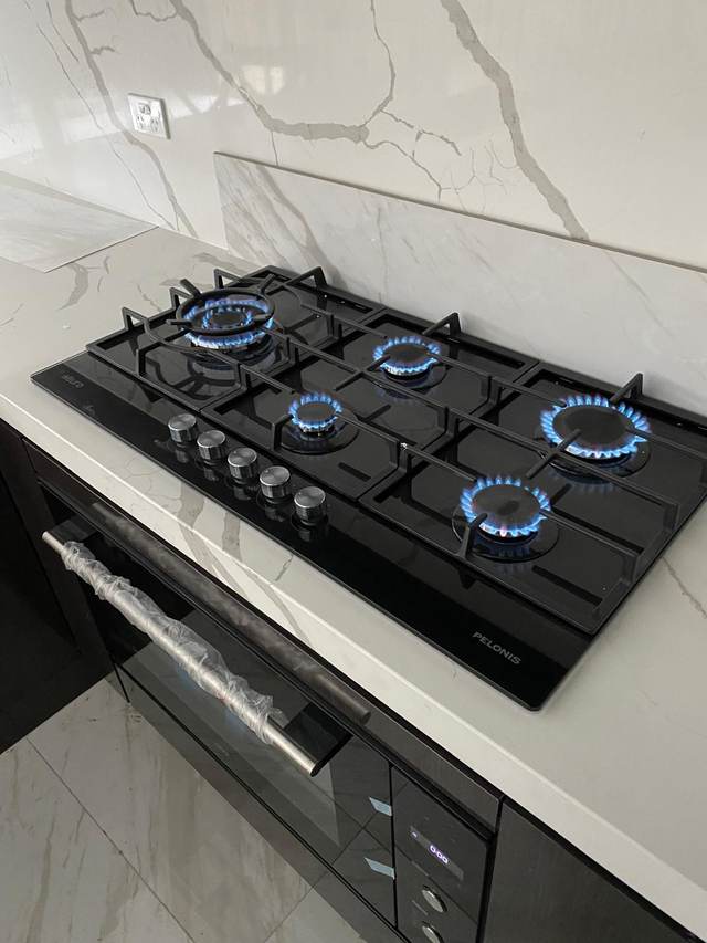 Five-burner gas cooktop alight after connection and testing during a kitchen gas fit-out
