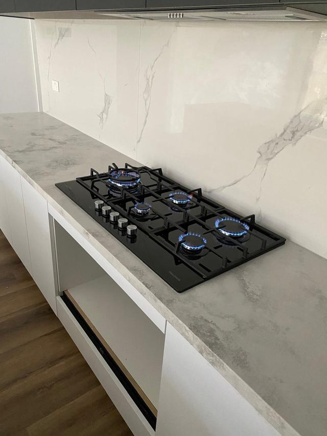 Five-burner gas cooktop alight in a new kitchen after connection and testing