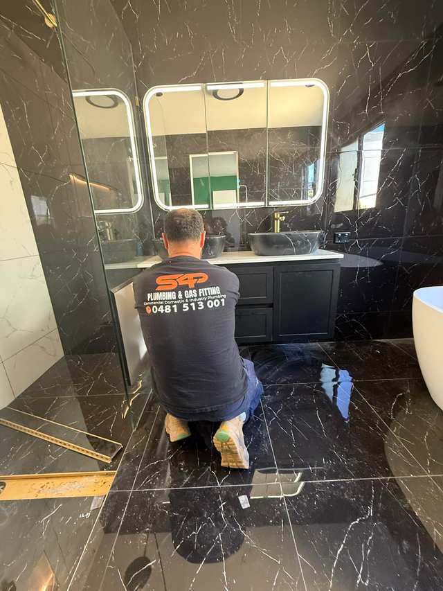An S4P plumber fitting off a vanity and tapware in a marble-tiled Melbourne bathroom